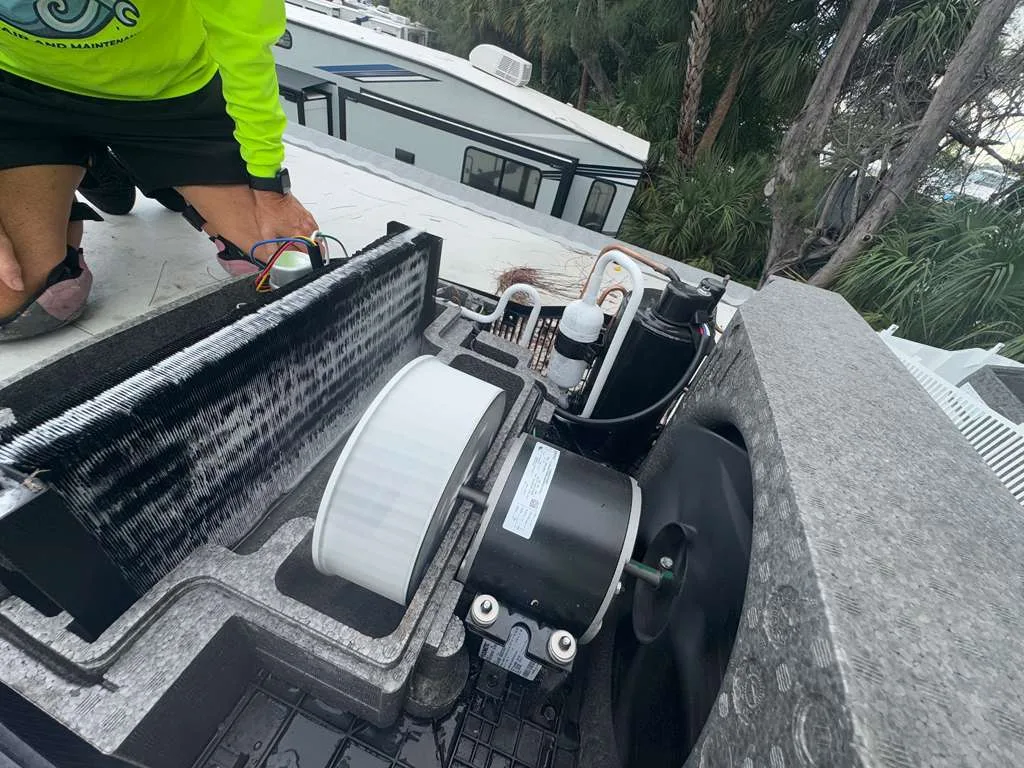 Technician working on an RV rooftop air conditioning unit during a Florida service call